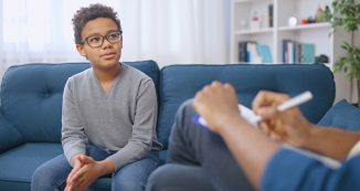 African American pre-teen boy having conversation with school psychologist, child therapy